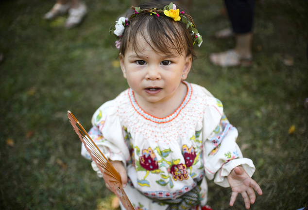 Eighteen-month-old Anastasia plays with a handheld fan during an event promoting the freedom of mothers to breastfeed in public, during World Breastfeeding Week, at the Village Museum, in Bucharest, Romania, Saturday, Aug. 6, 2016. (AP Photo/Andreea Alexandru)